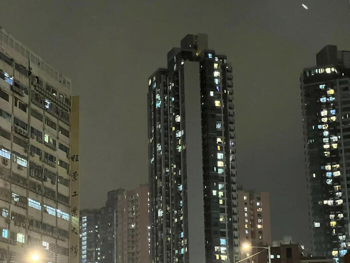City buildings at night showing a foggy sky that creates an optical illusion of a giant tidal wave.