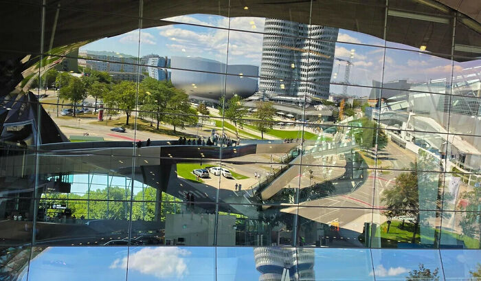A complex reflection on a glass building facade that requires looking twice to separate reality from reflection.