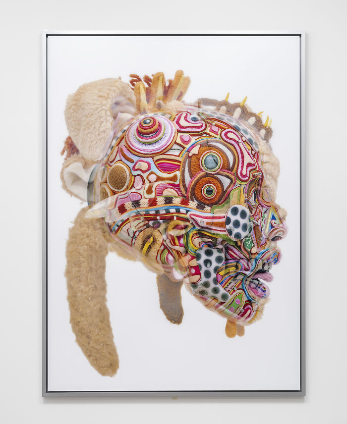 A detailed close-up of unusual sculptures showing a colorful face made of yarn and plush fabric