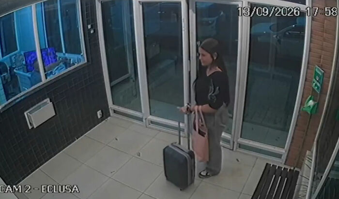 Security camera footage showing a daughter standing with her suitcase in a lobby. Security camera footage showing a daughter standing with her suitcase in a lobby.