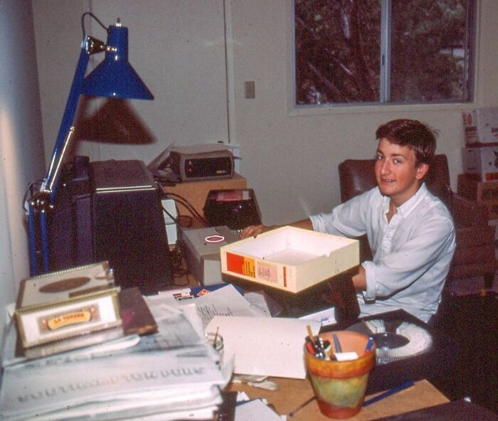 Man working with vintage computer tech and documents at desk