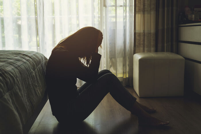 A silhouette of a person sitting on the floor, head in hands, symbolizing potential problems society faces.