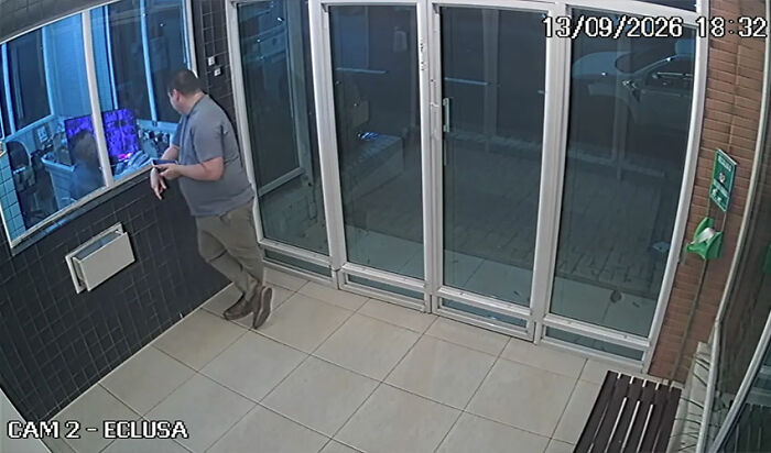 Security footage showing a boss standing near a glass door entryway Security footage showing a boss standing near a glass door entryway