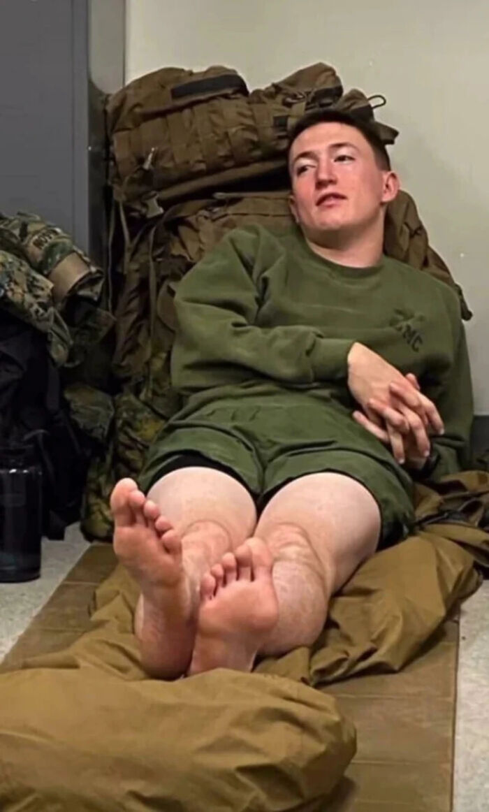 A soldier resting on gear creates a confusing perspective where his bare feet look reversed.