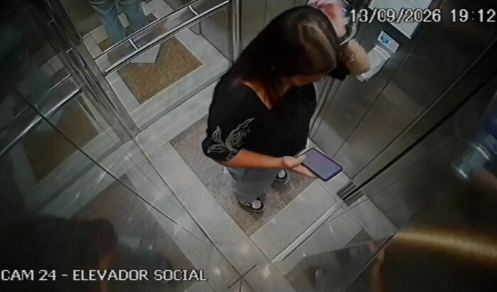 Dating her boss story: surveillance shot of a young woman checking her phone in an elevator Dating her boss story: surveillance shot of a young woman checking her phone in an elevator