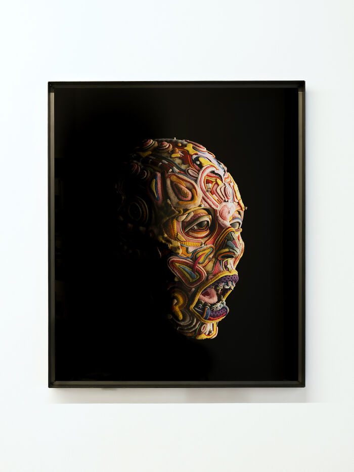 Framed portrait of a human face made of colorful textile patterns, showing unusual sculptures style.