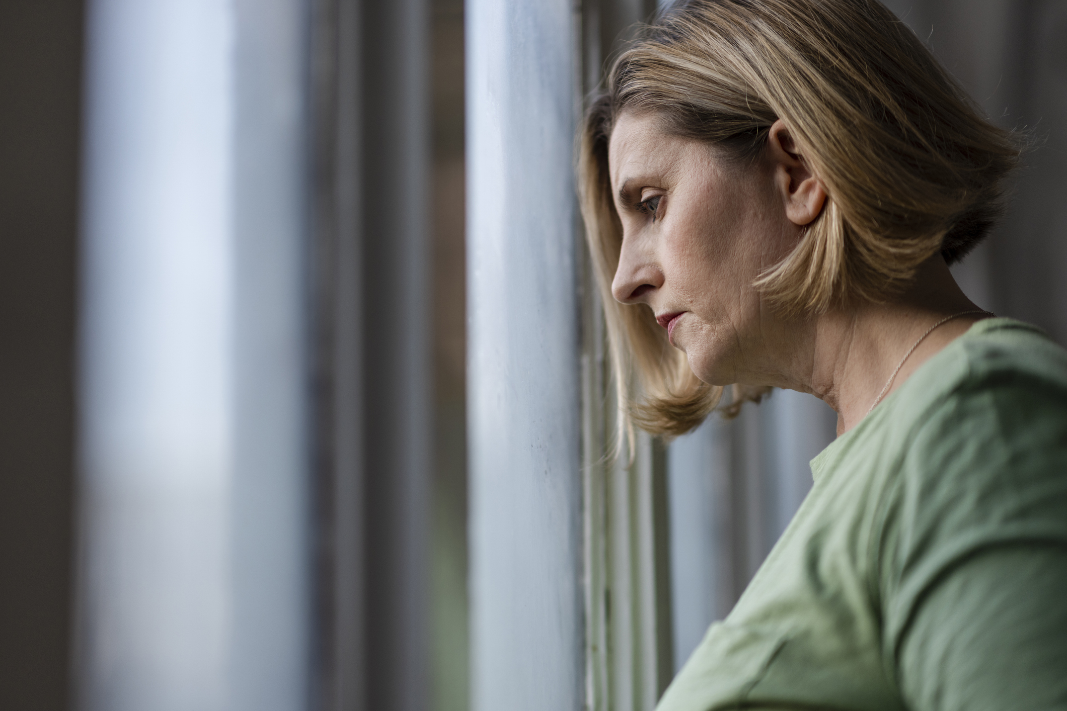 A sad grandmother looking out the window while thinking about her twin newborns abroad A sad grandmother looking out the window while thinking about her twin newborns abroad