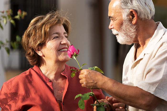 A senior man giving a rose to a senior woman, representing a MIL and her BF. A senior man giving a rose to a senior woman, representing a MIL and her BF.