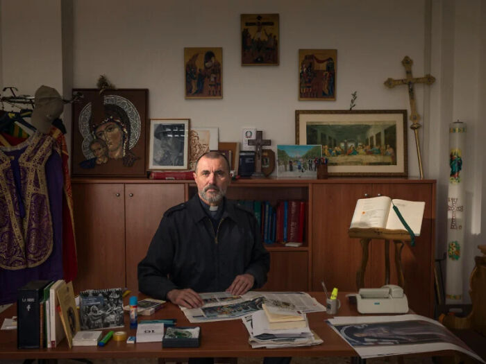 A photographer's project featuring a man in a clerical collar at a desk, part of a global look at people and offices of bureaucracy.