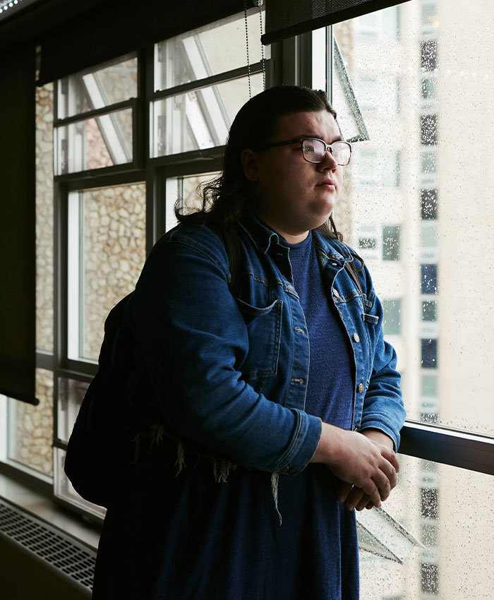 A person with glasses stands by a window, linked to the sorority sisters and national leadership case.