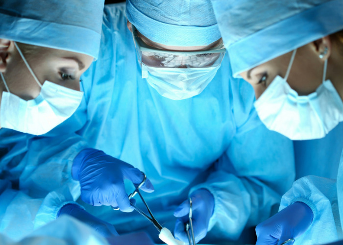 Close-up of surgeons focused on operation wearing blue surgical gowns