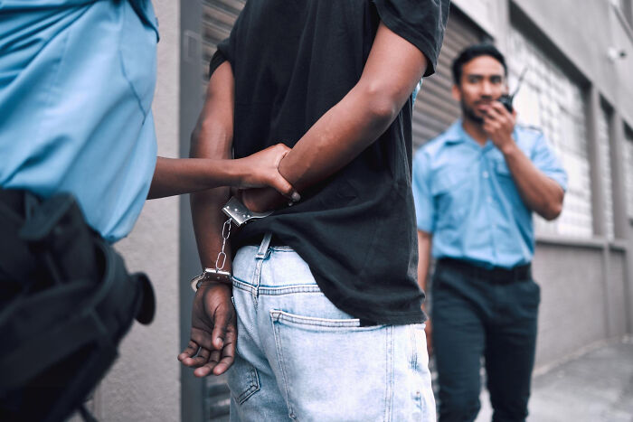 Police officers handcuffing a person, symbolizing dumb ways people ruin their lives through criminal actions.