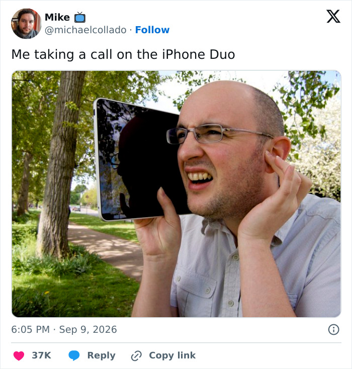 A man comically struggles to take a call using a large, unfolded iPhone in a park, reacting to the foldable iPhone mockery.