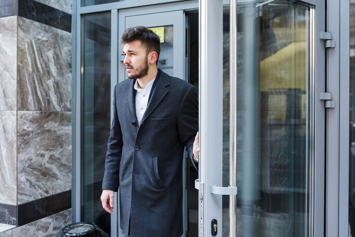 A man exits a building, a thing people do that others judge them for.
