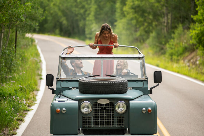 Friends enjoying an unexpected end to their life story, driving an old jeep on a scenic road.
