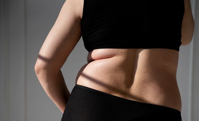 Rear view of a woman in black sportswear, highlighting body changes in her 30s and 40s.