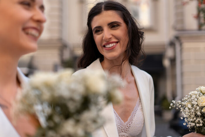 A happy smiling bride in a white outfit holding a flower bouquet, embodying the joy of weddings.