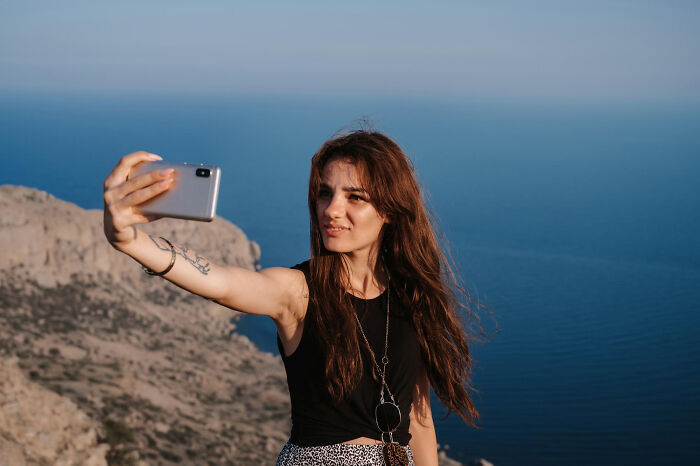 Woman taking a selfie by the ocean, capturing a moment before an unexpected end to her life story.