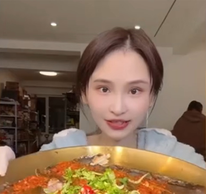 A mukbang star presenting a large plate of food, highlighting the dangers of extreme eating and dangerous condition.