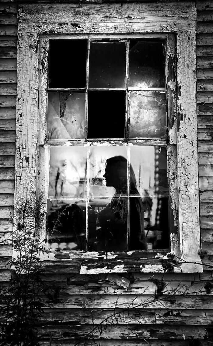 A haunting silhouette of a person reflected in a broken, weathered window, a compelling street photo from visual stories.
