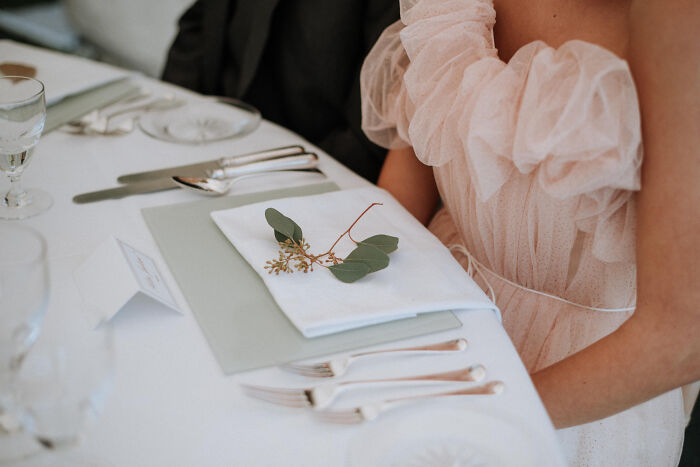 A bride in a pink ruffled gown sitting at a beautifully decorated reception table during weddings.
