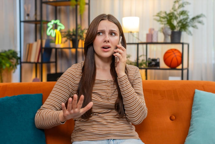 A woman on the phone, looking upset, indicating the struggle of being called a bad aunt.