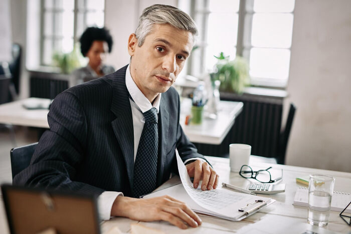 A thoughtful middle-aged businessman in a suit reviewing documents, highlighting satisfying stories