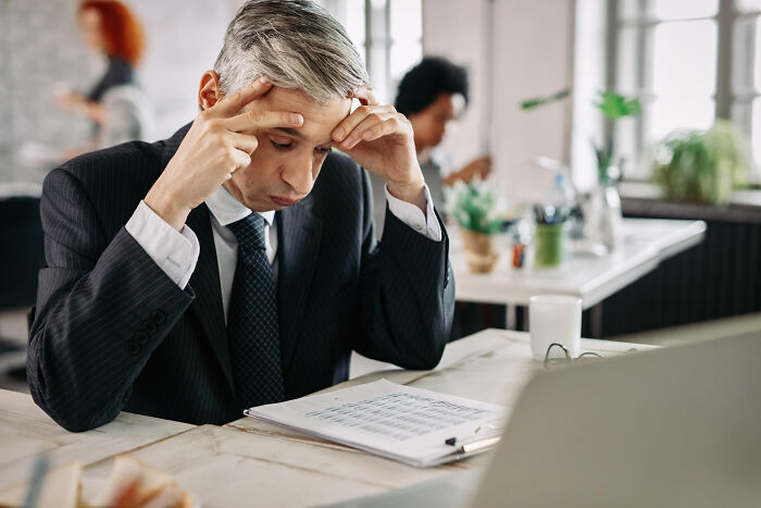 A stressed lawyer reviewing documents at his desk, highlighting the challenges lawyers face due to clients' poor choices.