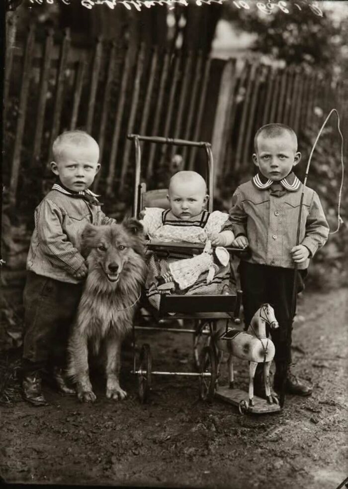 Three young children pose with their pet dog outdoors, an old photo of animals