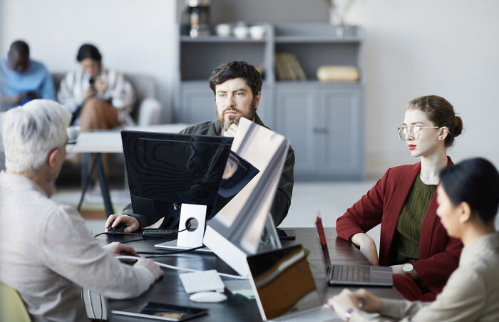 A diverse group of professionals working in an office, discussing the biggest problems society could be facing.