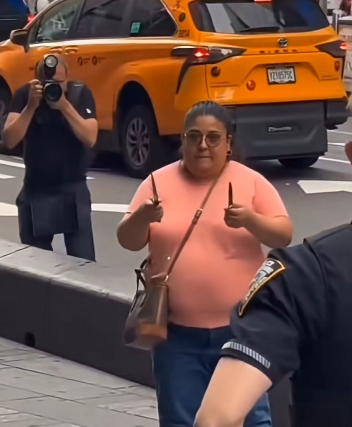 A woman holds two knives while confronting cops in Times Square during a dramatic video incident. A woman holds two knives while confronting cops in Times Square during a dramatic video incident.