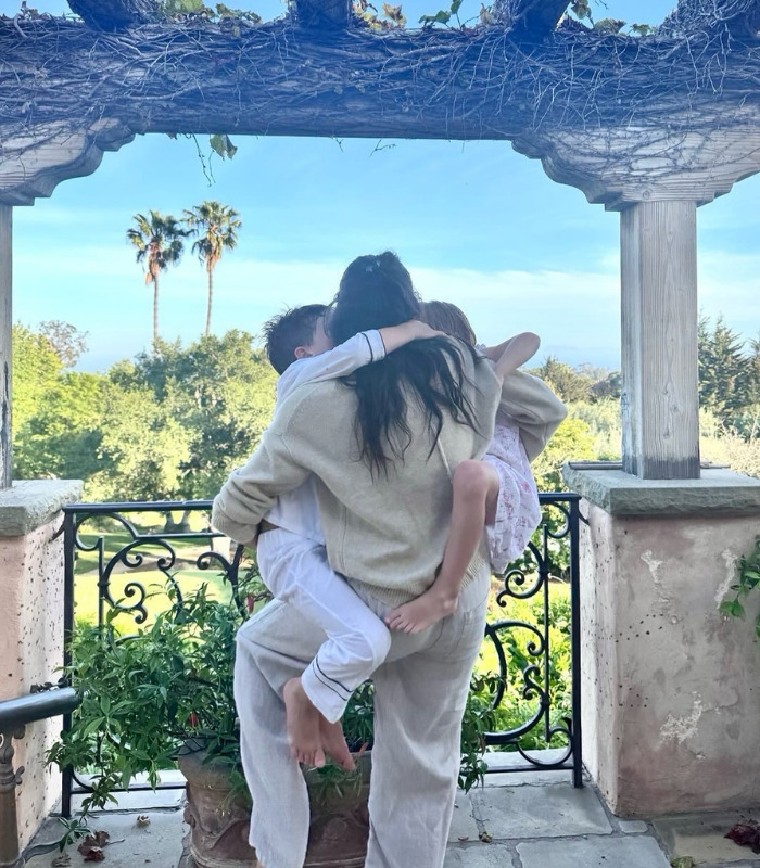 Meghan holds her children on a balcony, with palm trees in the background, amidst UK return tension. Meghan holds her children on a balcony, with palm trees in the background, amidst UK return tension.