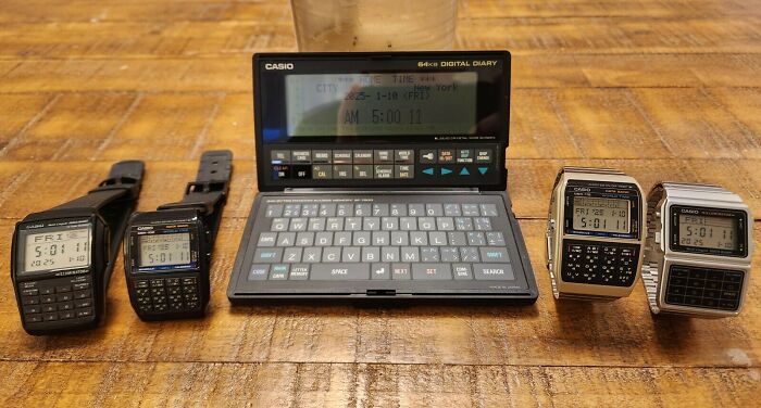An array of 80s retro tech Casio digital diaries and calculator watches, laid out on a wooden surface, highlighting vintage gadgets.
