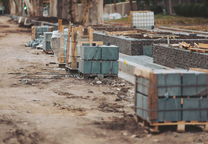 Construction workers have left a site with neatly stacked materials including stone blocks on pallets and fencing.
