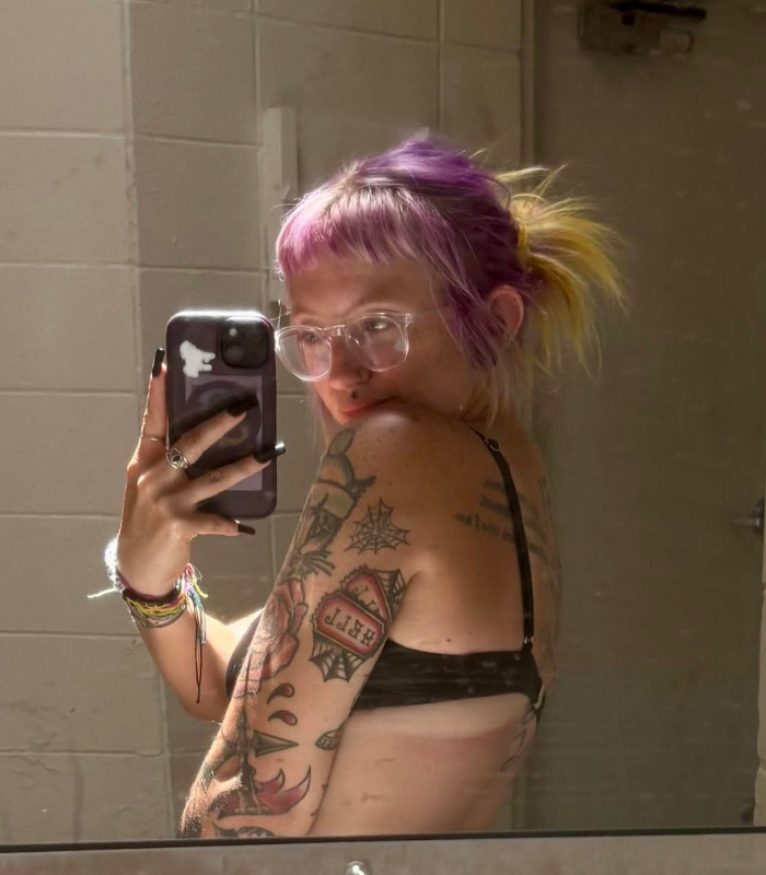 Woman with tattoos and colorful hair taking a mirror selfie, raising awareness about date rejection. Woman with tattoos and colorful hair taking a mirror selfie, raising awareness about date rejection.