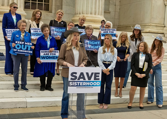 Sorority sisters gather with signs like Save Sisterhood in front of a federal court building.