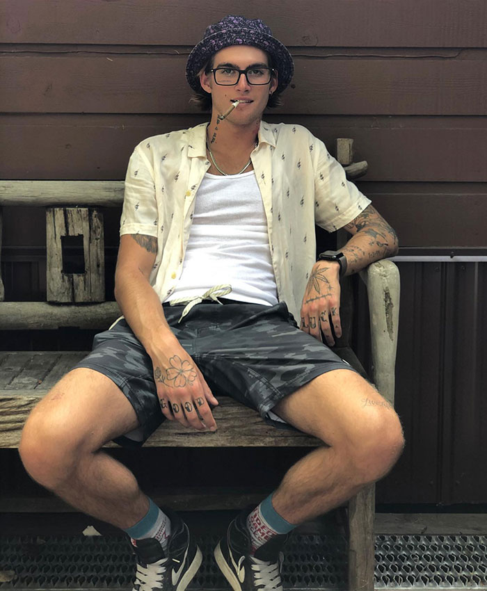 Presley Gerber wearing a bucket hat, sunglasses, and smoking a cigarette while sitting on a wooden bench. Presley Gerber wearing a bucket hat, sunglasses, and smoking a cigarette while sitting on a wooden bench.