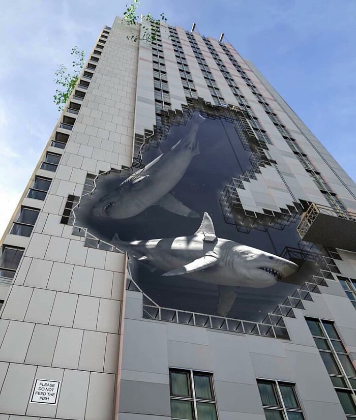 Massive street art of sharks swimming through a broken building facade.