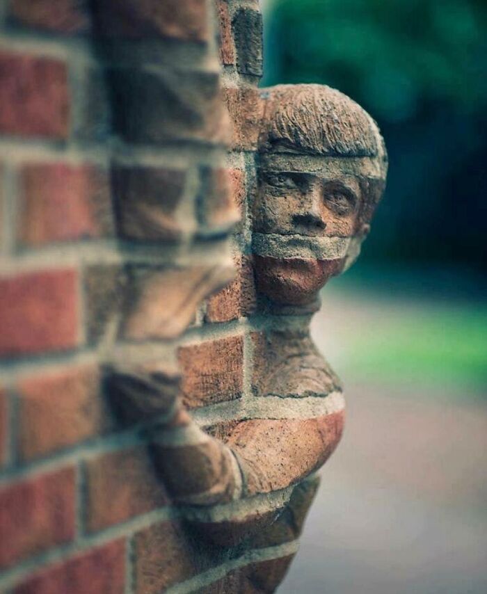 Intricate brickwork street art showing a figure emerging from a brick wall.