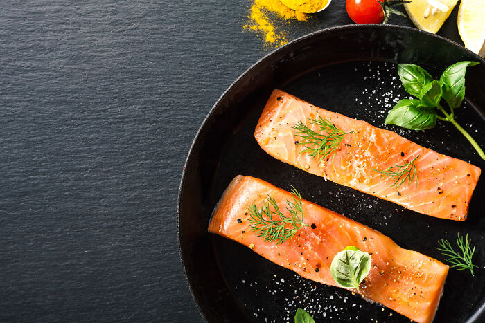 Two raw salmon fillets on a black plate, representing raw and unprepared court arguments.