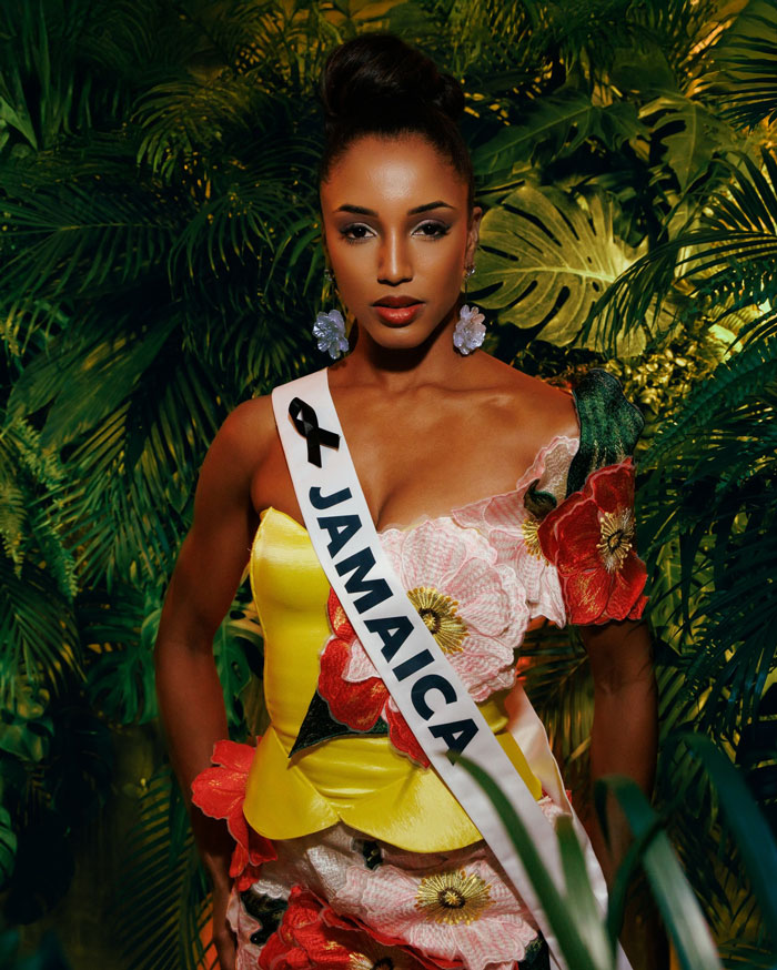 Miss Universe Jamaica Gabrielle Henry in a floral gown standing against lush green foliage background Miss Universe Jamaica Gabrielle Henry in a floral gown standing against lush green foliage background