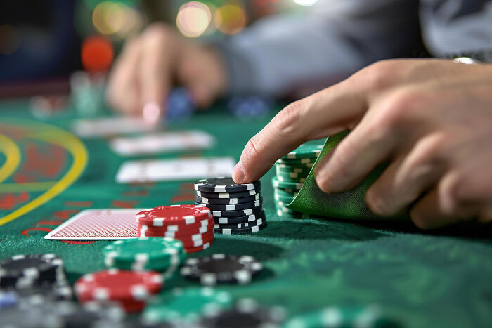Hands placing poker chips on a table, representing dumb ways people ruin their lives through gambling.
