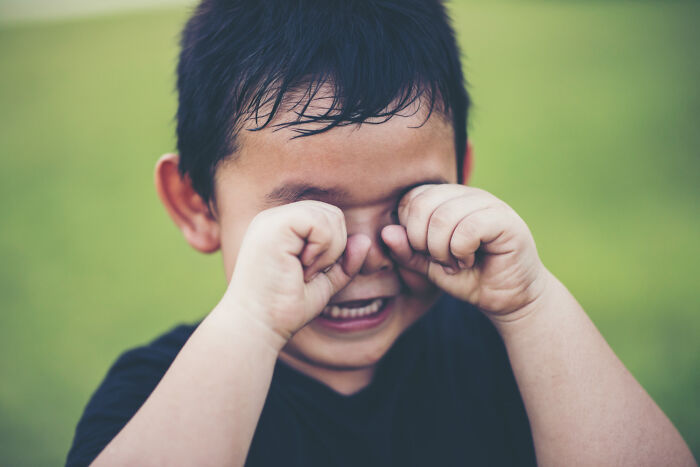 Young child rubbing eyes and crying, showing how strange patients express discomfort.