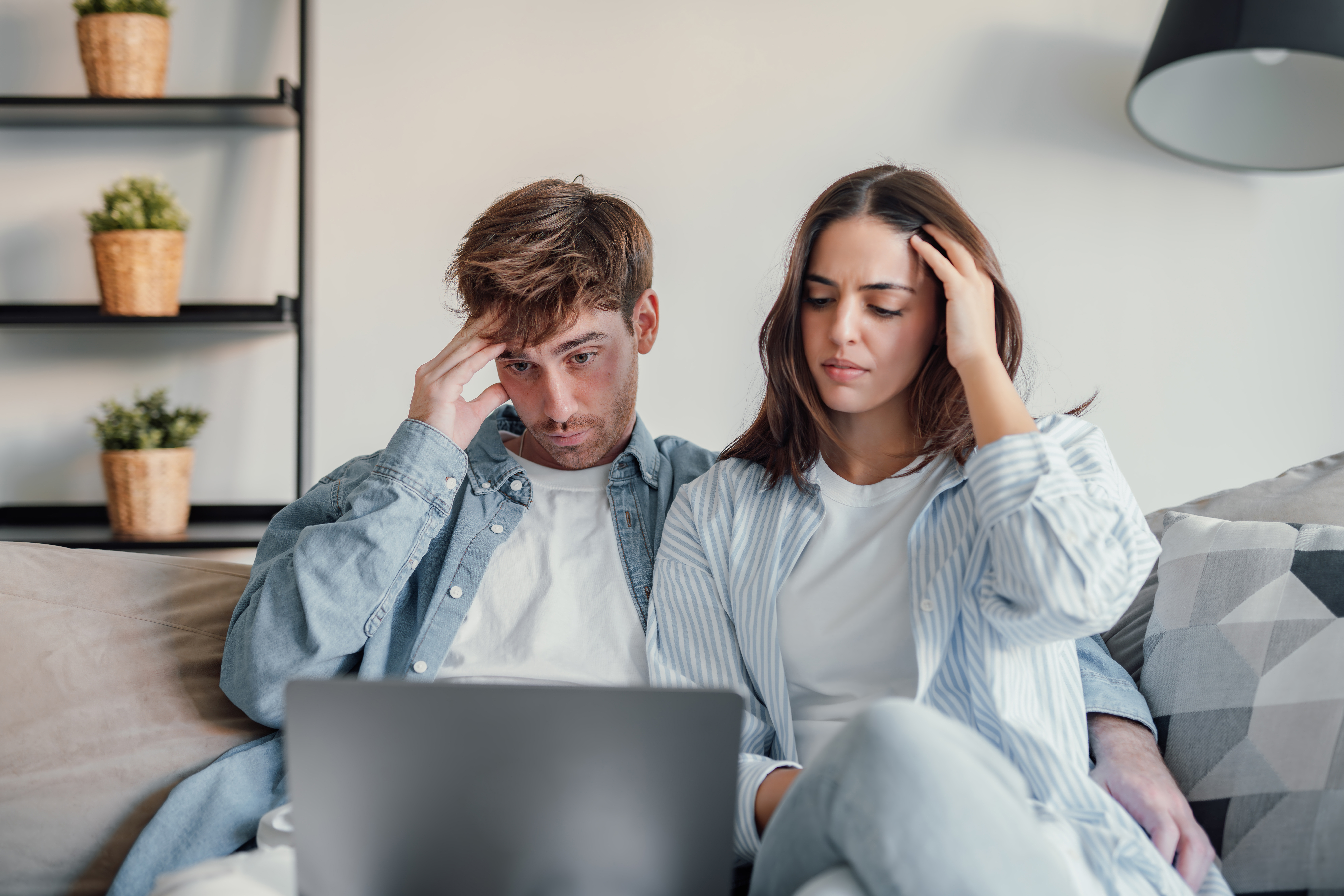 A stressed couple looking concerned while looking at a laptop screen, depicting a son and DIL upset. A stressed couple looking concerned while looking at a laptop screen, depicting a son and DIL upset.