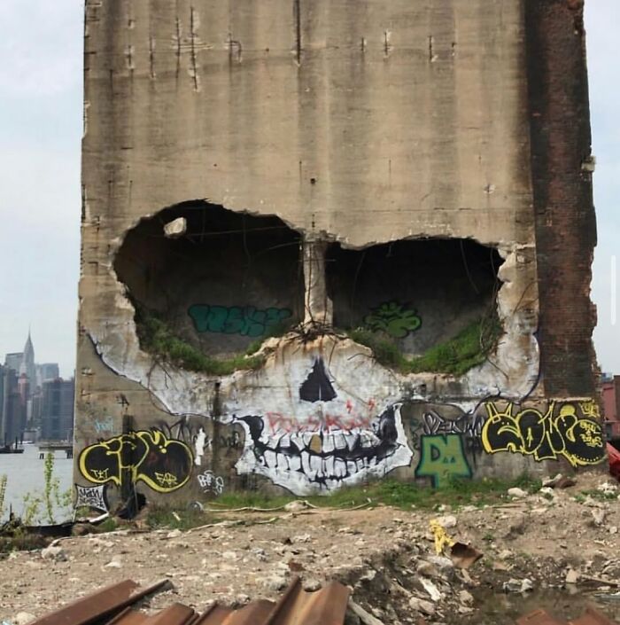 A massive skull-shaped street art mural on an old concrete silo, showcasing urban artistic expression.