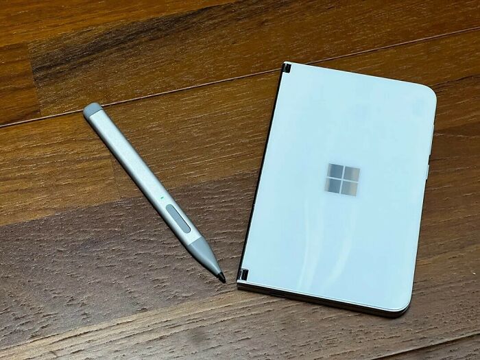 A modern white tablet device with a stylus pen on a wooden surface, highlighting contemporary tech.