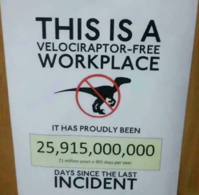 A chaotic sign reads 'THIS IS A VELOCIRAPTOR-FREE WORKPLACE' with a crossed-out dinosaur, claiming '25,915,000,000 DAYS SINCE THE LAST INCIDENT', making people question reality.