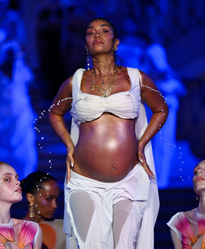 Pregnant star Leigh-Anne Pinnock poses on a runway during a bizarre appearance with gushing liquid.