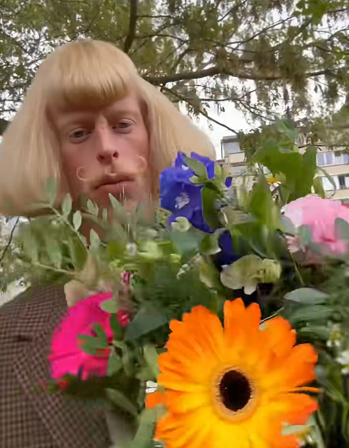 A mysterious influencer with a mustache holds a colorful bouquet of flowers