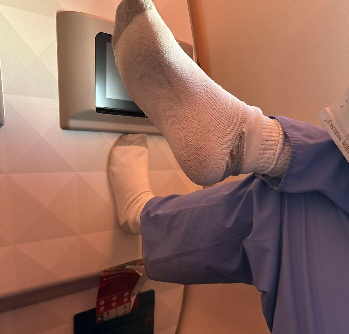 Rude passenger with socks on putting feet up on the screen, illustrating a plane seatmate from hell